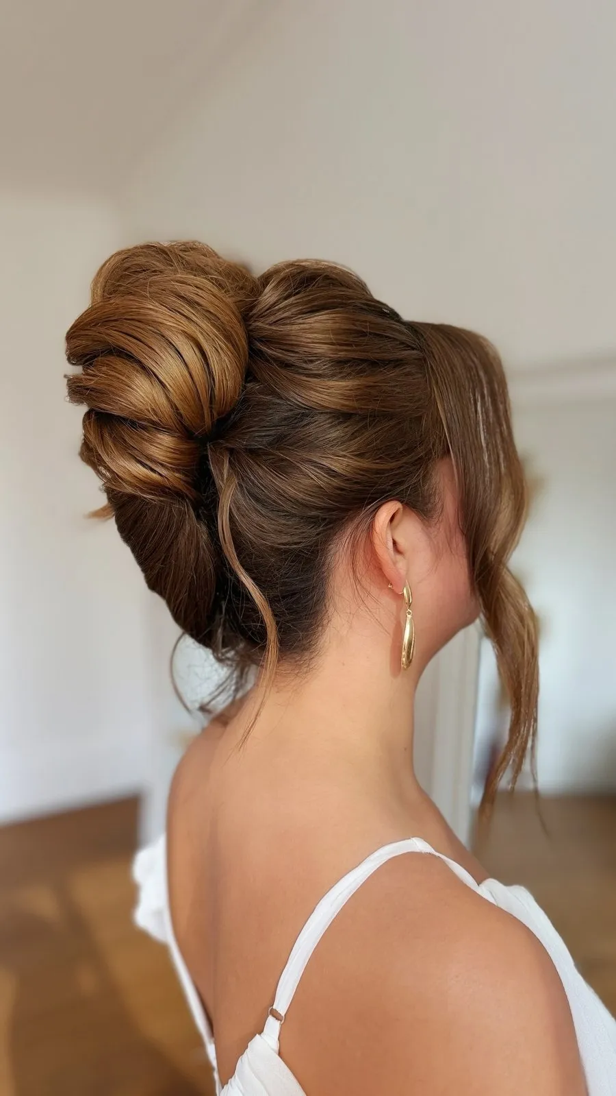 Chignon volumineux sur cheveux châtain cuivré, mèches libres