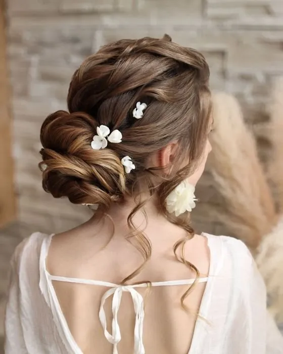 Chignon bohème bouclé orné de petites fleurs blanches