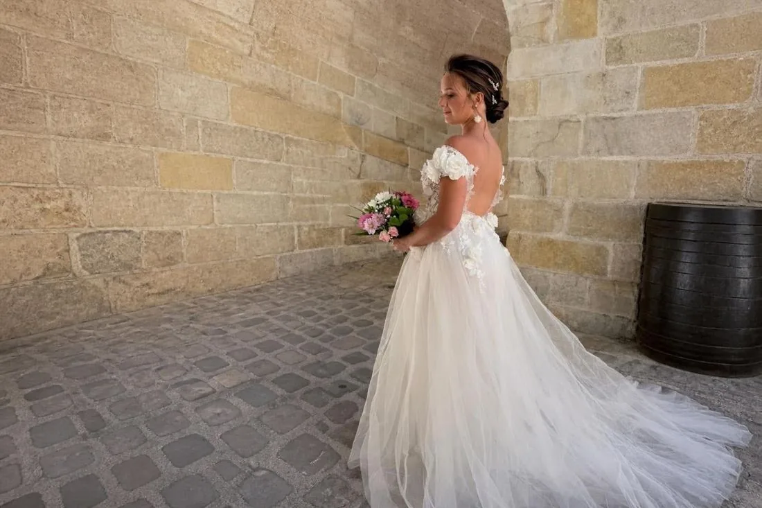 Mariée coiffée d'un chignon bas dans un passage en pierre